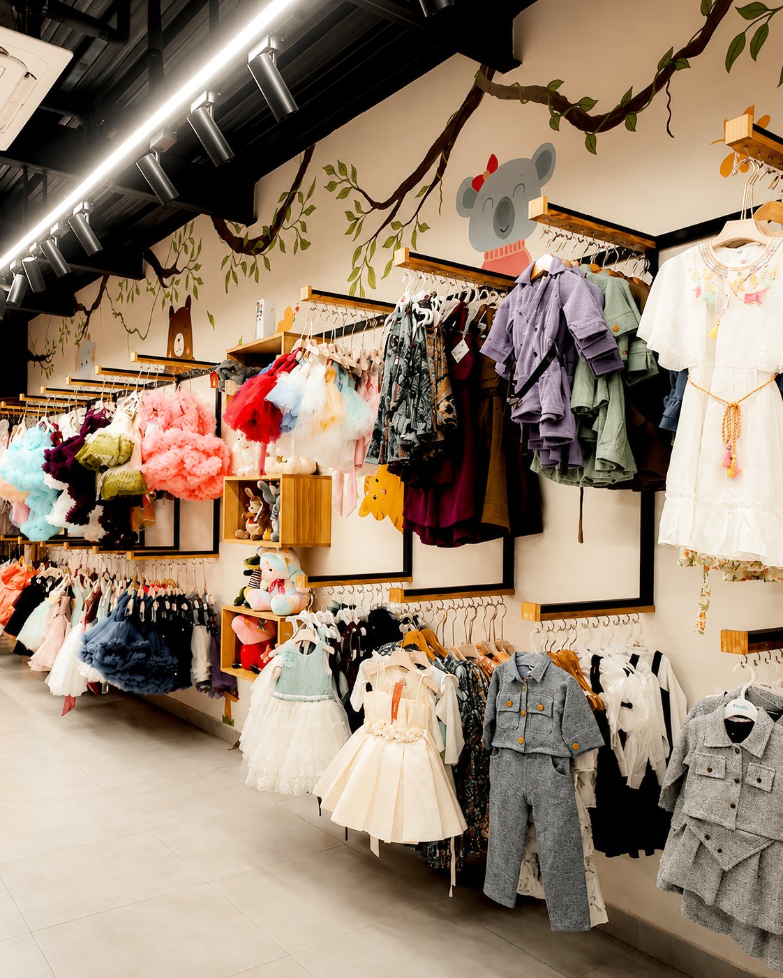 Children's clothing display beneath a painted tree branch and koala motif