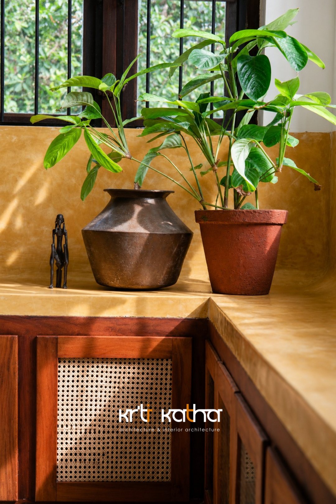 Leafy potted plants on an ochre counter above cane-fronted wood cabinetry