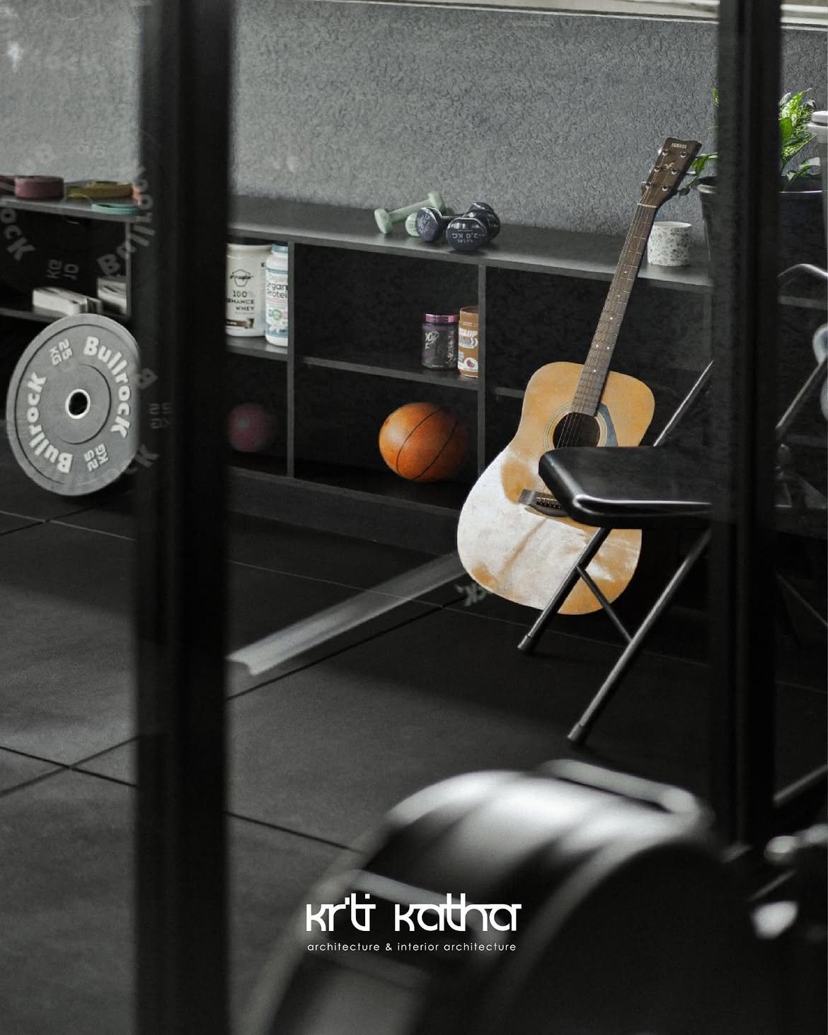 Acoustic guitar on a chair beside open gym storage holding balls and weight plates