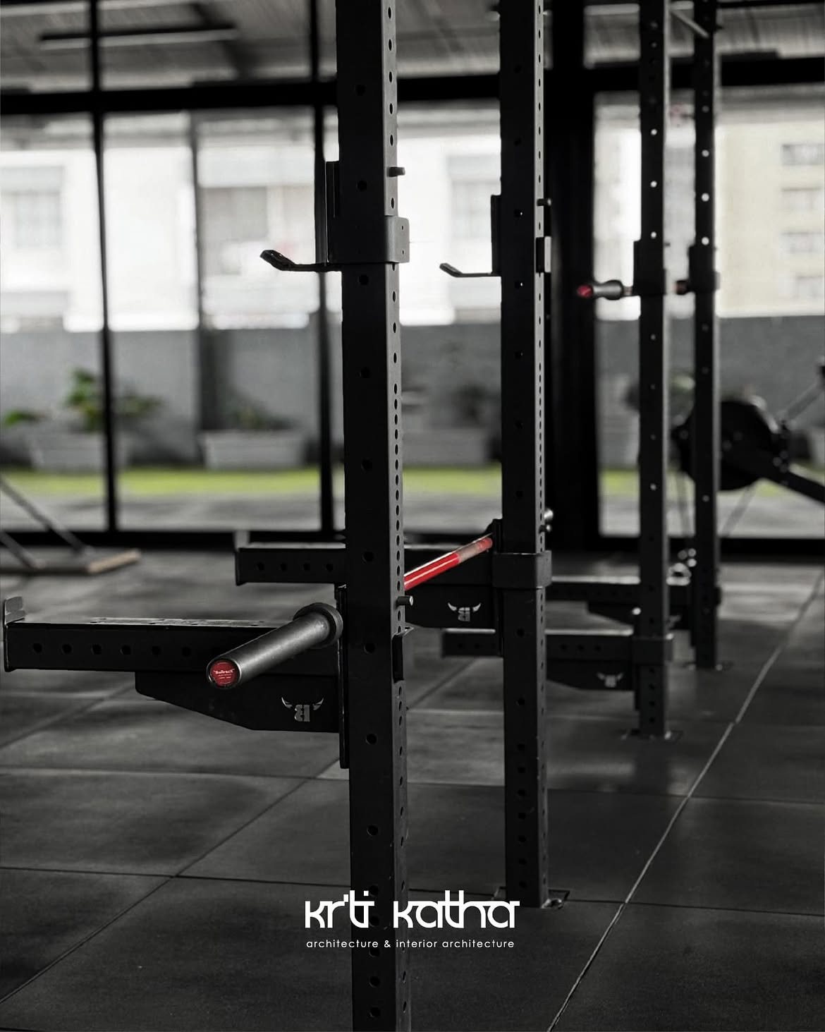 Close view along black squat-rack uprights and safety arms on rubber flooring