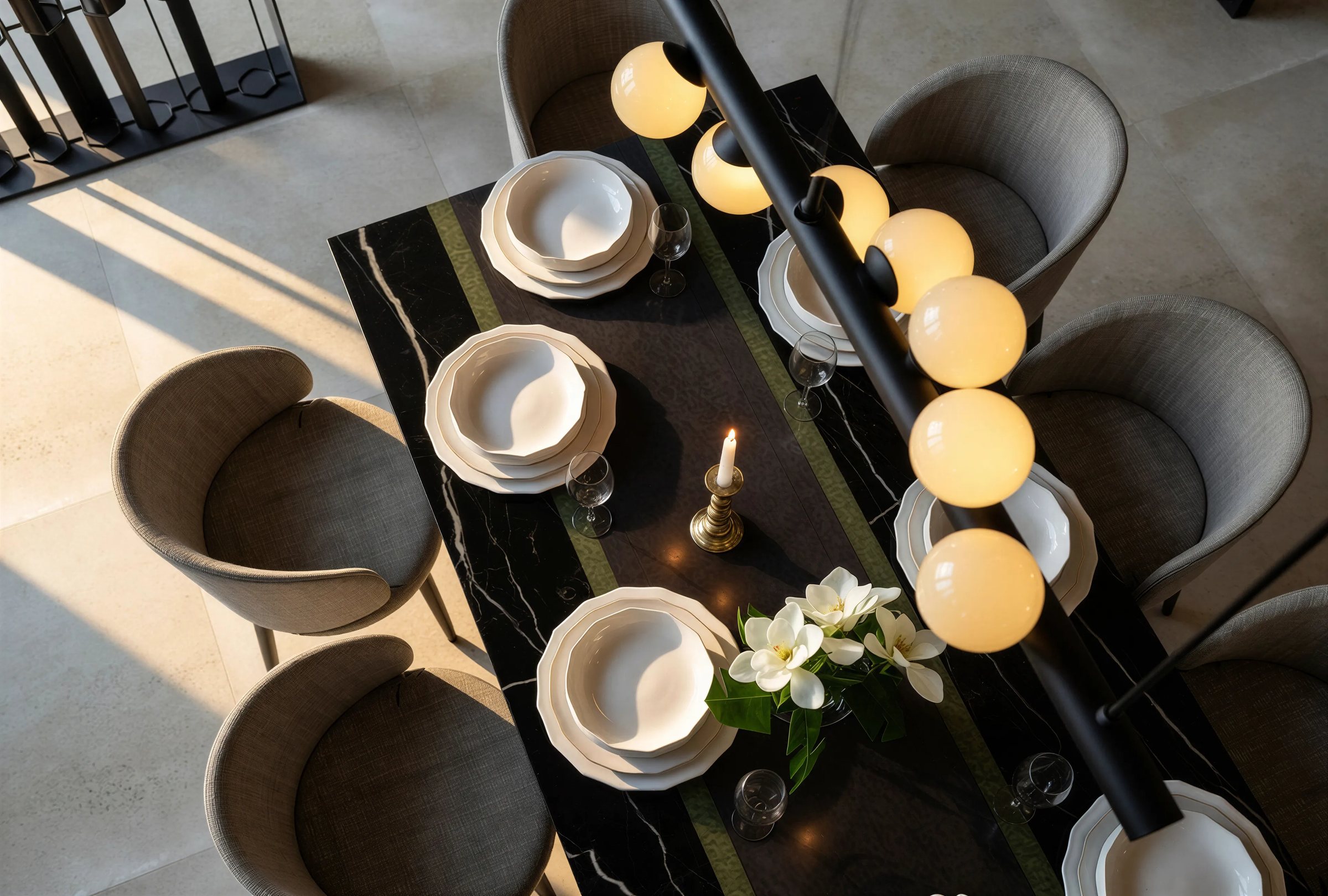 Overhead view of a set dining table beneath a linear row of glowing globe pendants